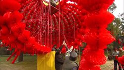 Men hoist red bands of flowers onto a structure during the Temple of Earth festival. Stock Footage