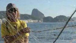 Brazilian fishermen untangle fishing net on Copacabana shore with Sugarloaf in background Stock Footage