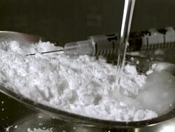 ECU SLO MO Drops of water falling into spoon with drug powder against black background / Vieux Pont, Normandy, France Stock Footage