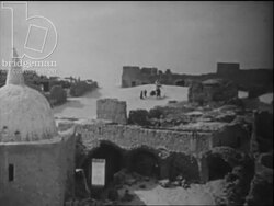 Wide shot of village in North African desert, family leaves on foot due to drought, c.1960 Stock Footage