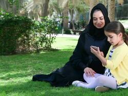 Arab mother and daughter enjoying with smartphone at park Stock Footage
