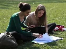 Teenage girls work on homework in park, using digital tablet Stock Footage
