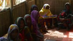 Women in colourful saris from a small village in Northern Bangladesh gather in the thatch meeting room for healthcare advice from an NGO Stock Footage