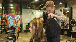 Male Hair stylist drying a female clients hair Stock Footage
