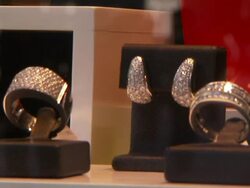 A jewelry store displays diamond earrings and bracelets in a window as shoppers walk by. Stock Footage