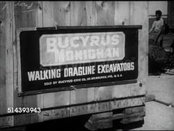 1953: KARACHI, WEST PAKISTAN: PORT: Angled WS Docked ship, WS 'Bucyrus Monighan walking dragline excavations' sign on wooden crate, possibly excavator. VS Men pushing railroad flatbed car loaded w/ large parts to next car on track.   Imports, exports, Instructional Video