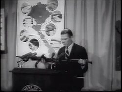 B/W 1965 zoom out Robert McNamara holding Chinese machine gun + talking at podium during Vietnam War Stock Footage