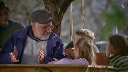 A grandfather sits under a tree telling a story to his grandchildren. Stock Footage