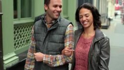 Happy New York couple walk arm-in-arm up sidewalk in Soho, girl kisses boyfriend's cheek Stock Footage