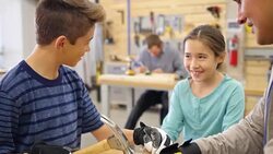 Mid adult Hispanic instructor at community workshop day camp teaches children how to hammer a nail into board Stock Footage