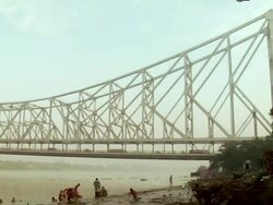 MS PAN View of Howrah bridge over hooghly river and people bathing near riverside  / Kolkata, west Bengal, India Stock Footage