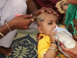Barber shaving head of a baby, Haridwar, Uttarakhand, India Stock Footage