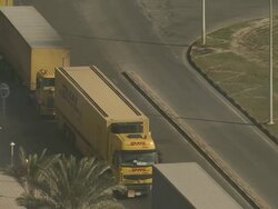 MS PAN TU TD Line of trucks waiting on corner of road near sign pointing to Coast Guard:/ Causeway ,Bahrain Stock Footage