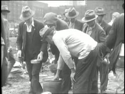 Men in a shanty town stand in line for soup and do their laundry. News Clip