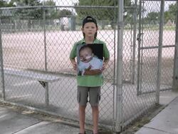 Slow motion push of boy standing and holding up picture of himself as baby. Stock Footage