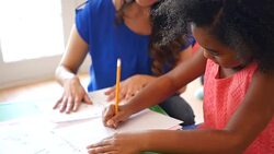 Elementary age girl works on math problems with teacher at daycare Stock Footage