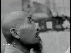 1944: NATIONALIST HSIEN SYSTEM: Farmer pushing wheat cart. Farmers gathered outside building. Agent explaining (no SOT) how system works. VS Chinese farmers. Man on platform, large Chinese crowd watching. Chinese women looking upward. CU Male farmer. Instructional Video