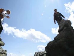 "Hikers jump between rocks on ridge crest, reach summit" Stock Footage