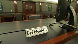 A defendant placard occupies a courtroom table. Stock Footage