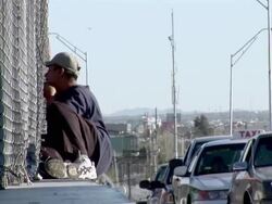 April 9 2009 WS ZI Man sitting by fence beside row of cars waiting at Mexican and US border, Juarez, Chihuahua, Mexico, AUDIO Stock Footage