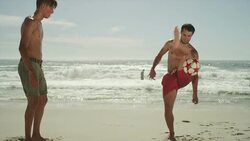 Young men kicking soccer ball on beach Stock Footage