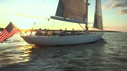 An American flag blows in the wind on the stern of the sailing yacht Heroina in Narragansett Bay at sunset. Stock Footage