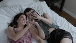 Young women on hotel bed look at smartphone and laugh Stock Footage