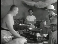 1940: FRENCH GUIANA (Iles du Salut): Wall sign: Cuisine. INT Butcher house, shirtless male cutting meat. Prisoners handing out meat portions, loaf of bread. CU Tin cup into window, meat into cup, greens on top. Convict eating (man BG very thin) Instructional Video