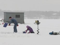 WS Father cleaning ice hole and preparing for fishing with daughter during winter / Minneapolis, Minnesota, USA Stock Footage
