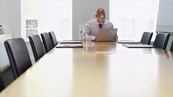 Smiling businessman at end of conference table using laptop Stock Footage