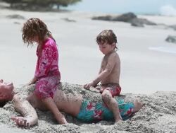 MS Boy and girl sit on man and play with sand on his body / Montezuma, Puntarenas, Costa Rica Stock Footage
