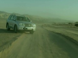 Vehicle driving in Wadi Araba desert with mountain back drop, Jordan Stock Footage