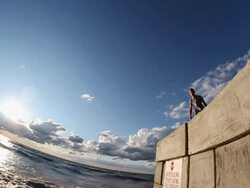 A young man jumping off a wall during sunset at the beach. - Slow Motion - Model Released - HD Stock Footage