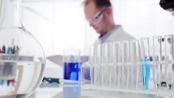 Scientist writing on clipboard behind test tube rack Stock Footage