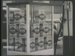 1935: PRESTONE ANTI-FREEZE: VS 'Prestone' antifreeze canisters for sale on table outside, behind glass panels. VS Males outside 'Barney's Garage,' looking at sample solution of Prestone in liter bottle. General Service Department investigation Instructional Video