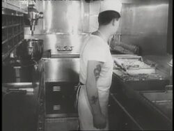 A tattooed cook flips steaks in the galley of the USS Nautilus. News Clip
