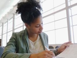 Trendy female adult student writing in notebook during study session in college library Stock Footage