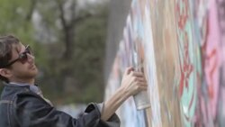 Young graffiti artist covers wall with spray paint Stock Footage