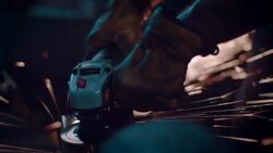 Man in motorcycle workshop grinding a piece of metal Stock Footage