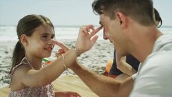 Father and daughter applying sunscreen to each other's faces Stock Footage