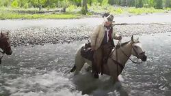 Cowboys crossing  a river on horseback Stock Footage