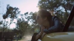 Young woman on road trip smiles as she leans out the back of classic car Stock Footage