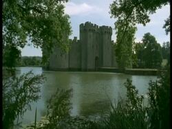 Bodiam Castle, Sussex - overhanging foreground trees, river Rother in foreground Stock Footage