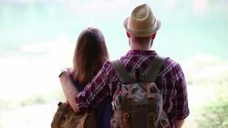 Young hipster couple backpacking looking at the lake Stock Footage