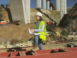 WS female site engineer checking plans in freeway bridge construction site Stock Footage