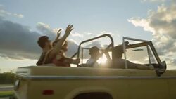 Friends on road trip in classic Bronco convertible throw hands in the air Stock Footage