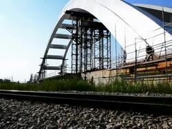 Arch bridge construction near railway lane and building bars Stock Footage