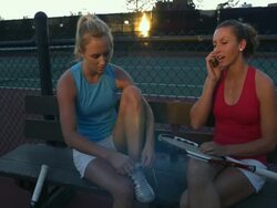MS, Two young women sitting on bench at tennis court, one talking on mobile phone, Santa Barbara, California, USA Stock Footage
