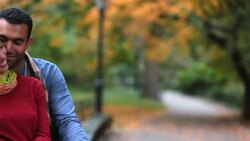 New York couple in love nuzzle on park-bench in Central Park, boyfriend kisses girl on cheek sweetly (dolly-shot) Stock Footage