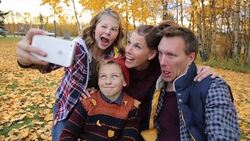 Family making silly faces taking a selfie in autumn park Stock Footage
